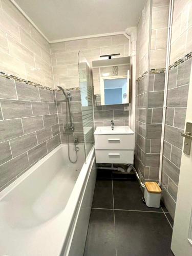 une salle de bain avec une baignoire, un lavabo et un miroir dans l'établissement Côté Sable, un balcon sur la mer - parking inclus, à Boulogne-sur-Mer