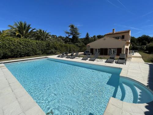 une piscine avec des chaises et une maison dans l'établissement VILLA LA LOUBIANE VI4428 By Riviera Holiday Homes, à Vence