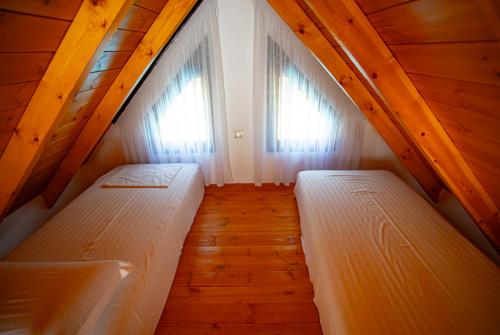 two beds in a room with two windows at Hotel & Restorant Flamuri in Lushnjë