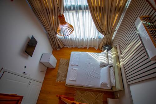 a bedroom with a white bed and a window at Hotel & Restorant Flamuri in Lushnjë