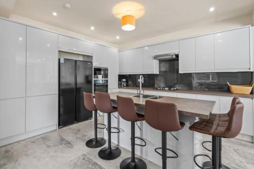 a kitchen with a wooden table and bar stools at LUXURIOUS HOLIDAY HOME Bolton in Bolton