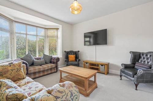 a living room with couches and a table and a tv at LUXURIOUS HOLIDAY HOME Bolton in Bolton