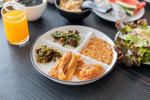 een tafel met borden en een glas sinaasappelsap bij Kokotel Pattaya North Beach in Noord Pattaya