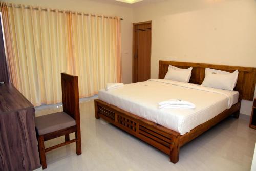 a bedroom with a large bed and a chair at Villa Varkala in Varkala