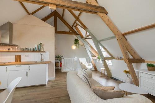 a kitchen and living room with white furniture and wooden beams at Zuss & Sleep Koudekerke in Koudekerke
