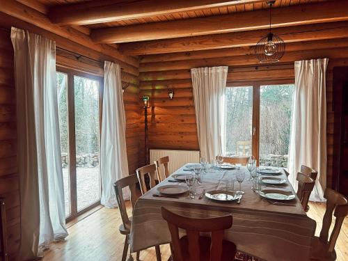 a dining room with a table with chairs and windows at Dein gemütliches Waldhaus im Soonwald in Henau