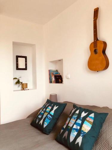 a bedroom with a guitar on the wall and a bed at Repülőhal Apartmanház in Zebegény