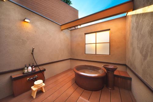 a bathroom with a tub in the corner of a house at Meitei no Yado Hotel Koshien in Fuefuki