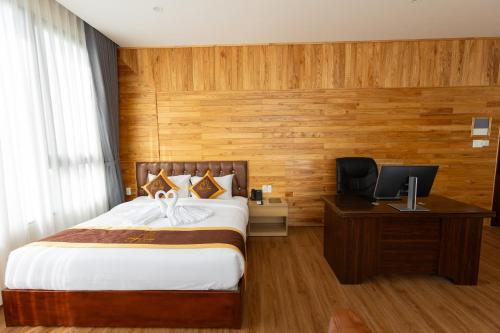 a bedroom with a bed and a desk with a television at LuckyStar Hotel in Pleiku