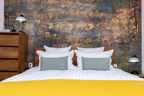 a bed with white pillows and a painting on the wall at Apartament Octavia in Hunedoara