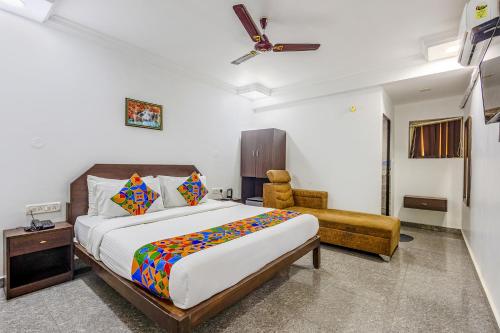 a bedroom with a large bed and a chair at FabHotel Raj Resort in Calangute