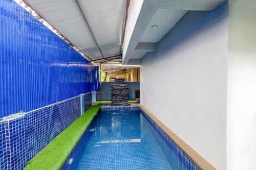 an empty swimming pool with a blue wall and green floor at FabHotel Raj Resort in Calangute