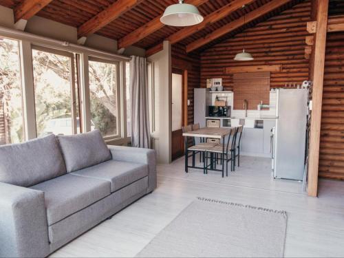 a living room with a couch and a table and a kitchen at Riverside Self Catering Cabin in Wilderness