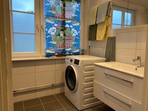 a washing machine in a bathroom with a window at Stor lägenhet ovanpå café ute på landet in Hökerum