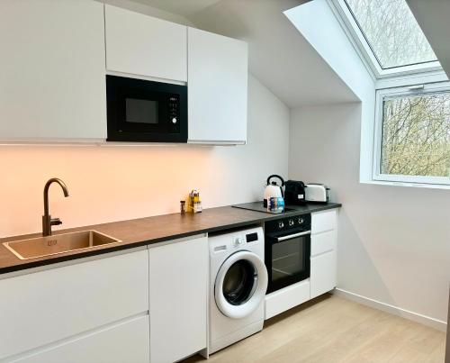 une cuisine blanche avec un évier et une machine à laver dans l'établissement Le Golfeur - DISNEY 15 min - PARIS 30 min - PARKING - Vue Golf - Lumineux & Moderne - Free WIFI, à Bussy-Saint-Georges
