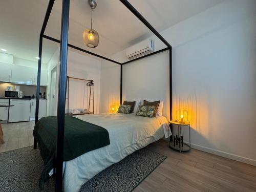 a bedroom with a canopy bed and a kitchen at DDM Studio - O paraíso do Sítio da Nazaré in Nazaré
