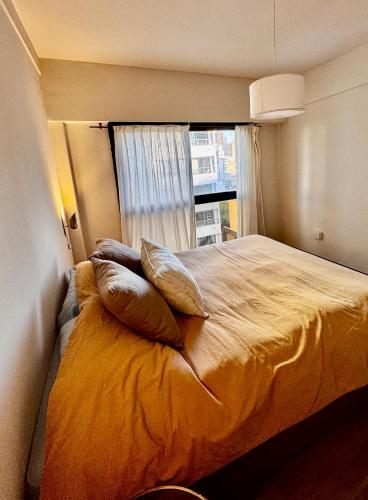 a bedroom with a bed with pillows and a window at Departamento Suite del Teatro in La Plata