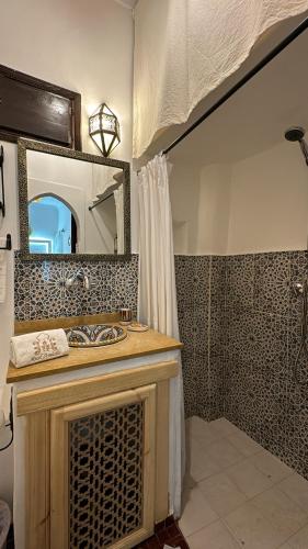 a bathroom with a sink and a mirror and a shower at Riad Andalla in Marrakesh