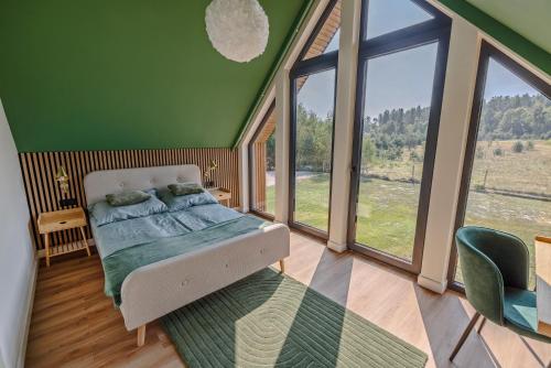 a bedroom with a bed in a room with windows at Luxury Villa in Liva Park - dostęp do basenu, całoroczne jacuzzi, grill, prywatny ogrodzony teren in Liwa