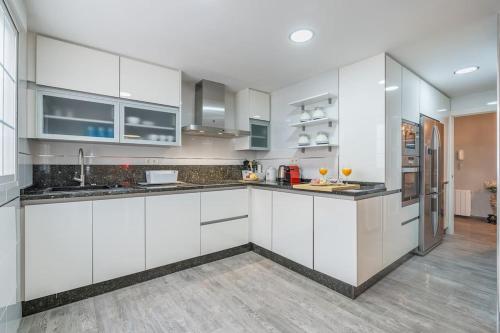 a white kitchen with white cabinets and a wooden floor at Luxury suite Reino de Granada in Granada