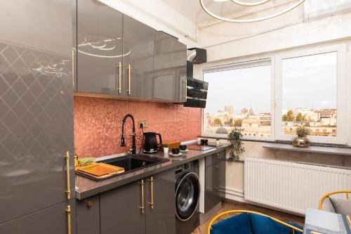 a kitchen with a sink and a washing machine at Royalty Apartment with City Views on Calea Victoriei in Bucharest