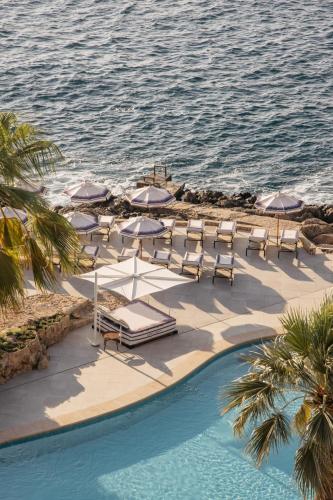 a group of lounge chairs and umbrellas next to a swimming pool at Hotel de Mar Gran Meliá - Adults Only - The Leading Hotels of the World in Illetas