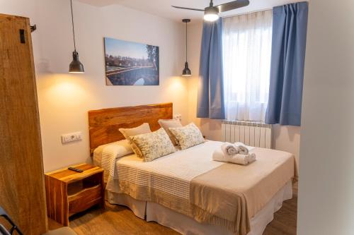 圣埃斯特万德戈尔马斯Hotel Rural La Bodega del Baldomero的一间卧室配有床和蓝色窗帘的窗户