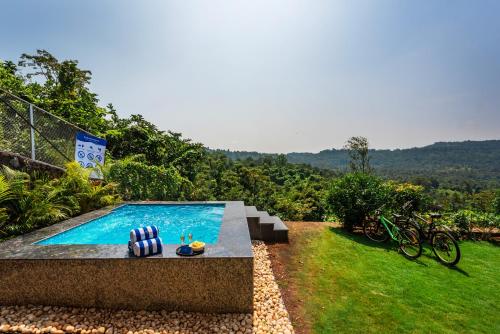 a swimming pool in a garden with a view at SaffronStays Whistling Winds in Pali