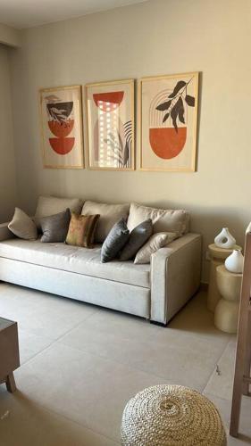 a couch in a living room with pictures on the wall at Stylish 1BR Ground With Free Pool & Lagoon Access In Gouna in Hurghada