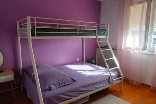 Ce lit superposé se trouve dans un dortoir doté d'un mur violet. dans l'établissement Appartement- étage villa - Villeneuve de la Raho, à Villeneuve-de-la-Raho