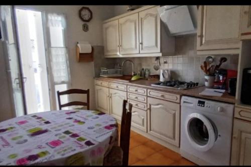 une cuisine avec une table et une machine à laver dans l'établissement Appartement- étage villa - Villeneuve de la Raho, à Villeneuve-de-la-Raho