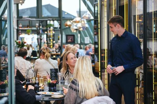 a man standing in a restaurant talking to people at Hotel Keflavik by Reykjavik Keflavik Airport in Keflavík