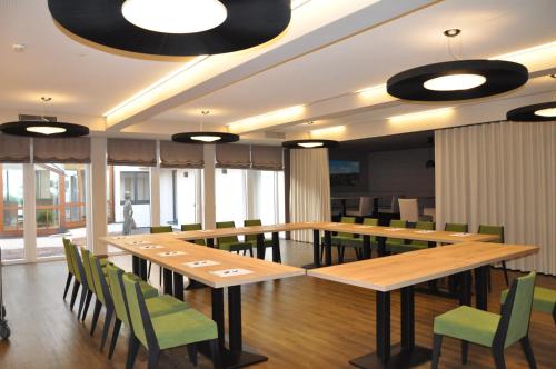 a dining room with wooden tables and green chairs at Sankt Magdalena in Linz