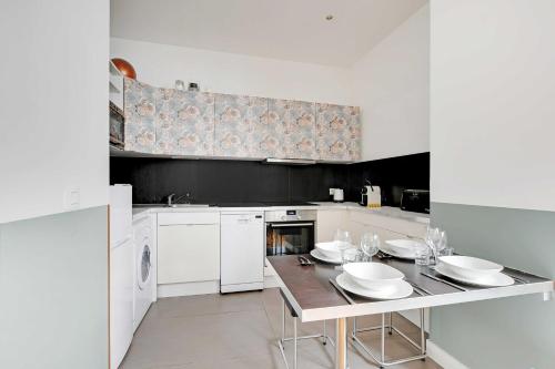 - une cuisine avec une table et des plats blancs dans l'établissement Charming apartment - 1BR-6P - Sentier, à Paris