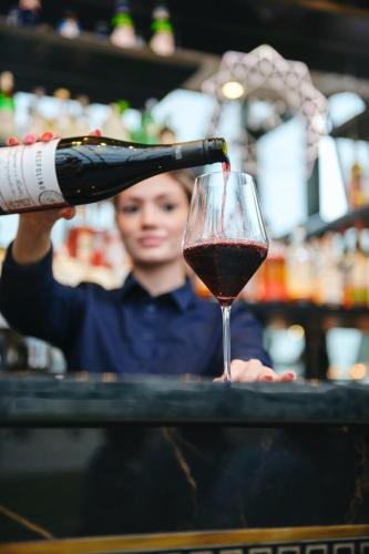 a woman pouring a bottle of wine into a wine glass at Hotel Keflavik by Reykjavik Keflavik Airport in Keflavík