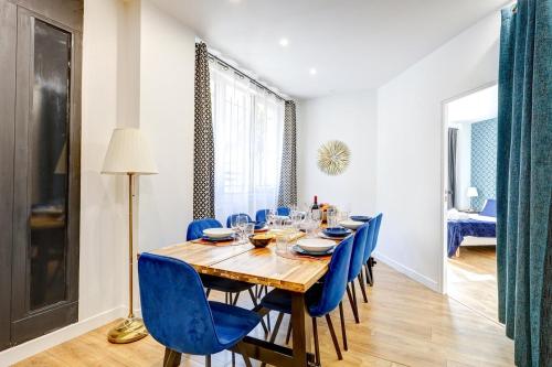 une salle à manger avec une table en bois et des chaises bleues dans l'établissement Bluestay 20 - Superb apartment in Paris, à Paris