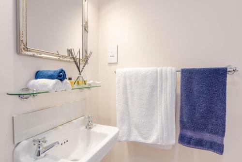 a bathroom with a sink and a mirror and towels at Sunny Cove Manor in Fish hoek