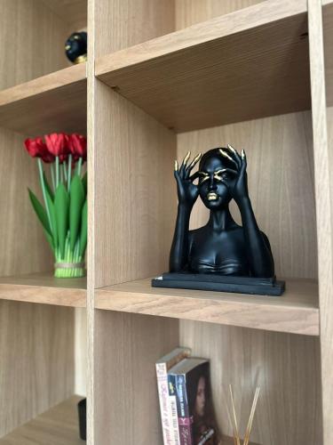 a statue of a woman with her hands up on a shelf at Vila 66 in Korçë