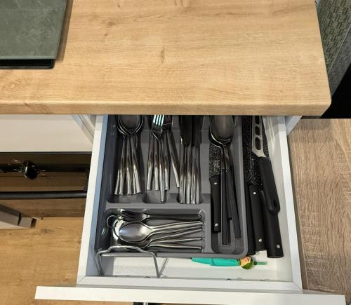 un tiroir rempli d'ustensiles dans une armoire dans l'établissement Le Fancy - 6 pers, proche Stade, centre commercial, à Villeneuve-la-Garenne