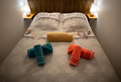 a bed with three different colored towels on it at Le Cyprès - Appartement idéal pour vos vacances ou vos déplacements professionnels à Béziers in Béziers