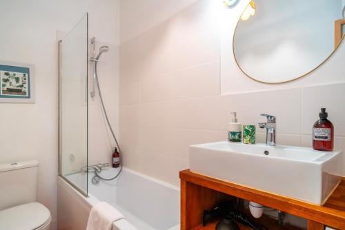 une salle de bain blanche avec un lavabo et une douche dans l'établissement Escale jardin - Joli apt proche gare avec jardin, à Vannes
