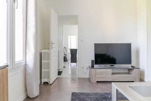 a white living room with a television and a table at Superbe maisonette avec parking privé à Villejuif in Villejuif