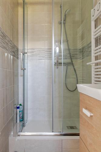 une douche avec une porte vitrée dans une salle de bain dans l'établissement Superbe maisonette avec parking privé à Villejuif, à Villejuif