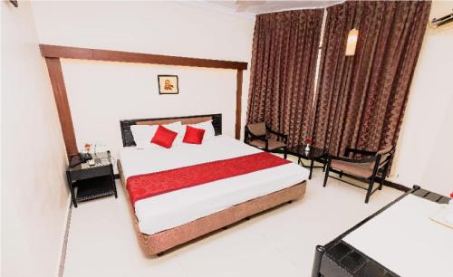 a bedroom with a bed with red pillows and a television at Hotel Garden in Navi Mumbai