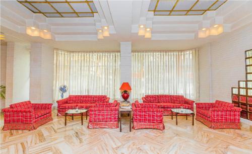 a living room with red couches and a table at Hotel Garden in Navi Mumbai