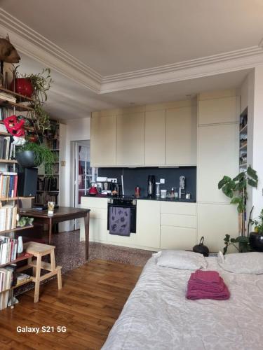 a bedroom with a bed and a table and a kitchen at Le Nid D'Aigle in Paris