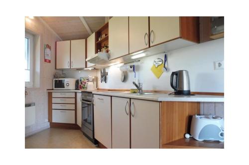 a kitchen with white cabinets and a sink at Ferienhaus Ty Glaz in Wesselburenerkoog