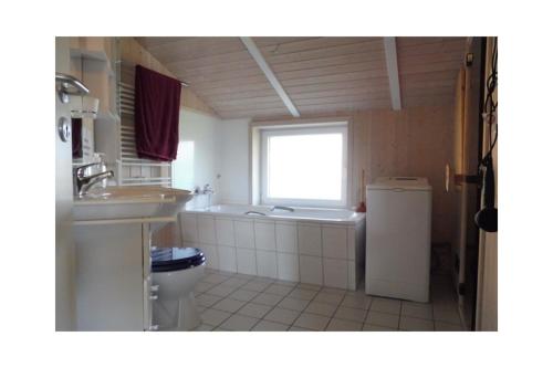 a bathroom with a sink and a toilet and a window at Ferienhaus Ty Glaz in Wesselburenerkoog