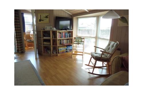 a living room with a chair and a television at Ferienhaus Ty Glaz in Wesselburenerkoog