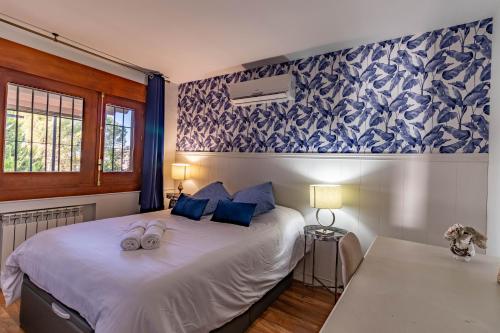 sypialnia z dużym białym łóżkiem i niebieskimi poduszkami w obiekcie RentitSpain Grand Luxury Villa Piscina & Jacuzzi Granada w mieście Albolote